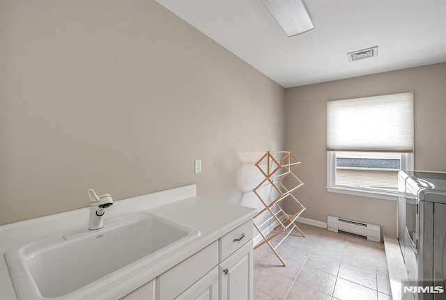 washroom with sink, a baseboard radiator, light tile patterned flooring, and cabinets