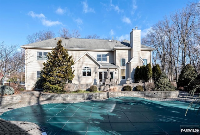 back of property with a covered pool and a patio area