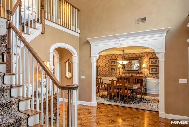 entrance foyer featuring ornate columns, a high ceiling, and parquet floors