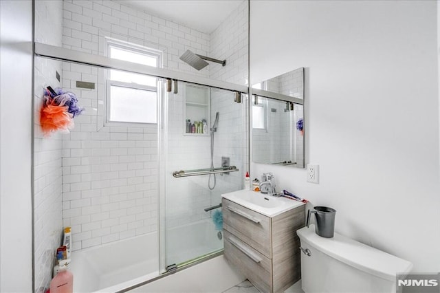 full bathroom featuring toilet, bath / shower combo with glass door, and vanity