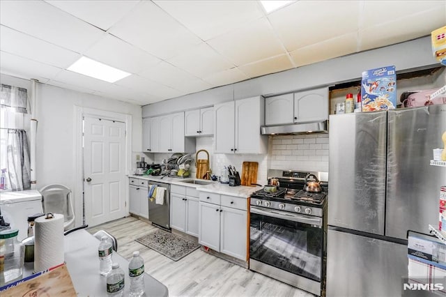 kitchen featuring light hardwood / wood-style floors, appliances with stainless steel finishes, tasteful backsplash, a drop ceiling, and sink