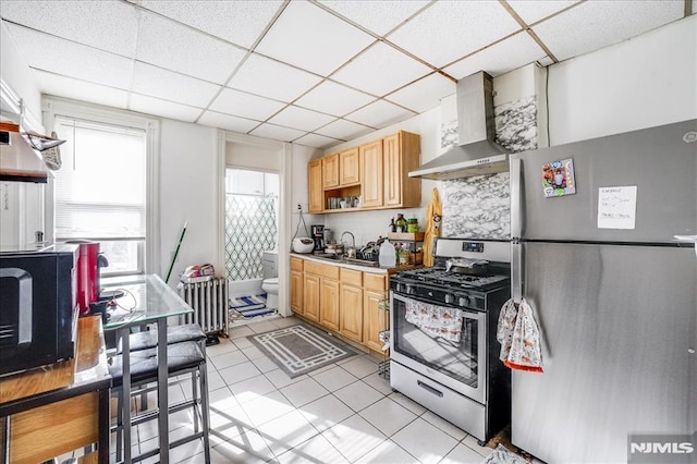 kitchen featuring light brown cabinets, stainless steel appliances, wall chimney exhaust hood, and backsplash