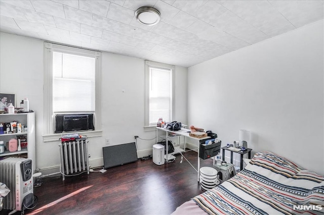 bedroom with cooling unit, dark hardwood / wood-style flooring, and radiator heating unit