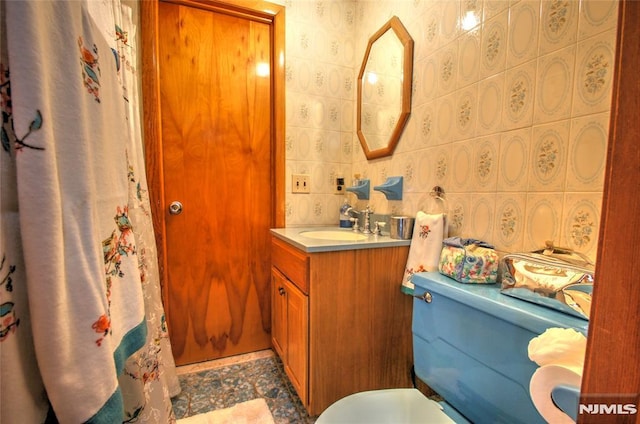 bathroom featuring toilet, vanity, tile walls, and backsplash