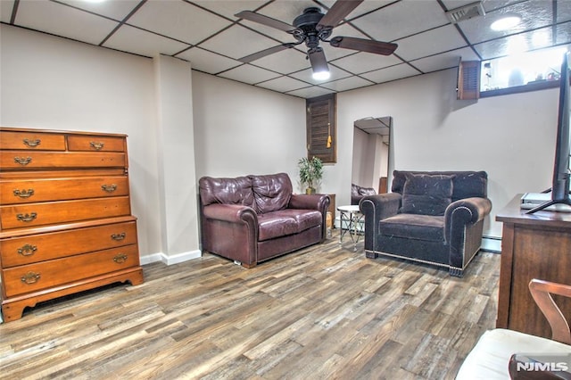 living room featuring baseboard heating, a drop ceiling, ceiling fan, and wood-type flooring