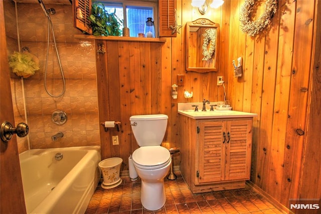 full bathroom with toilet, vanity, wood walls, and tiled shower / bath combo