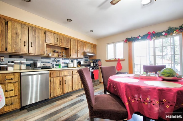 kitchen with ceiling fan, appliances with stainless steel finishes, light hardwood / wood-style floors, and backsplash