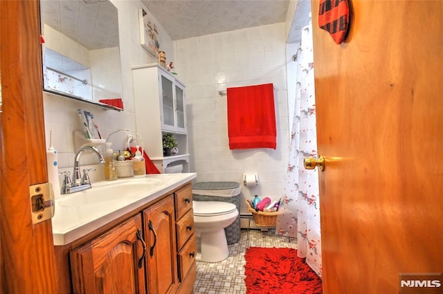 bathroom featuring toilet, vanity, and tile walls