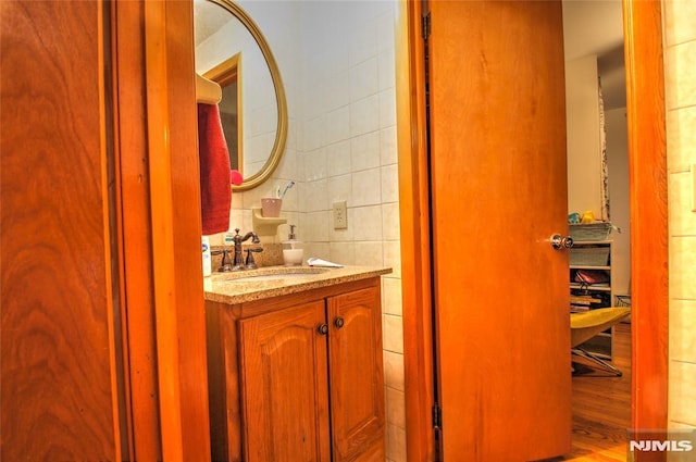 bathroom with tile walls, vanity, and hardwood / wood-style floors