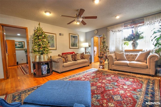 living room featuring a textured ceiling, ceiling fan, and light hardwood / wood-style floors