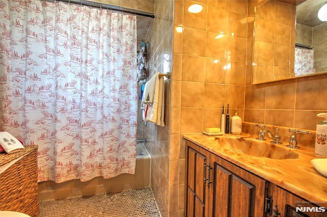 bathroom featuring tile walls, shower / bath combination with curtain, and vanity