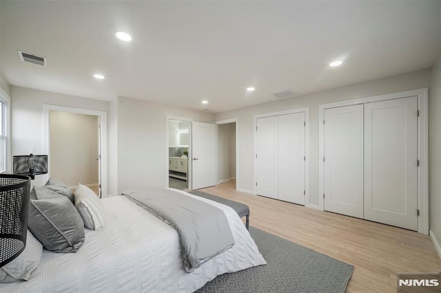 bedroom with two closets and light hardwood / wood-style flooring