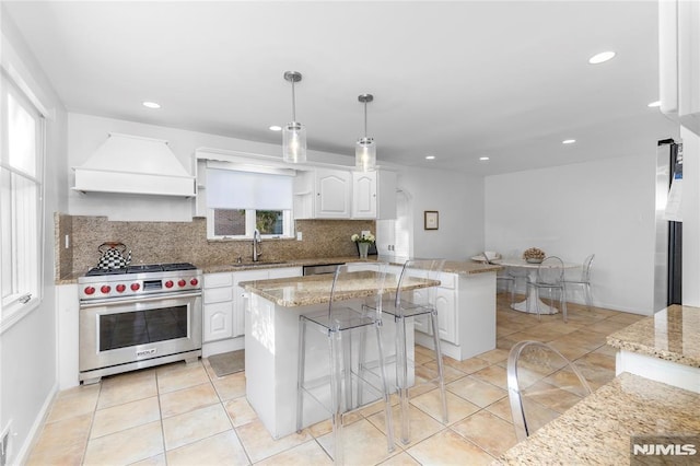 kitchen featuring white cabinets, custom range hood, a kitchen island, pendant lighting, and appliances with stainless steel finishes