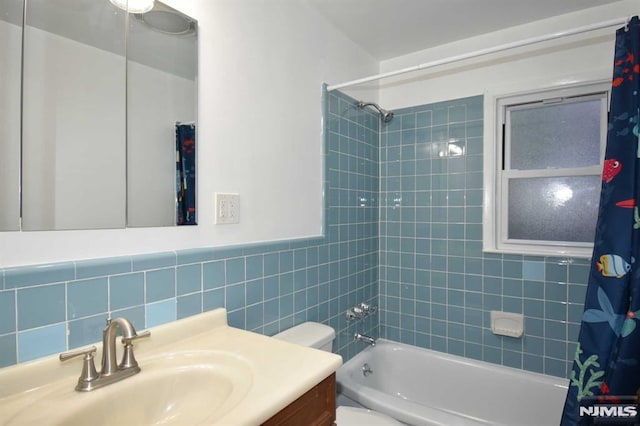 full bathroom with tile walls, vanity, shower / bath combo with shower curtain, and toilet