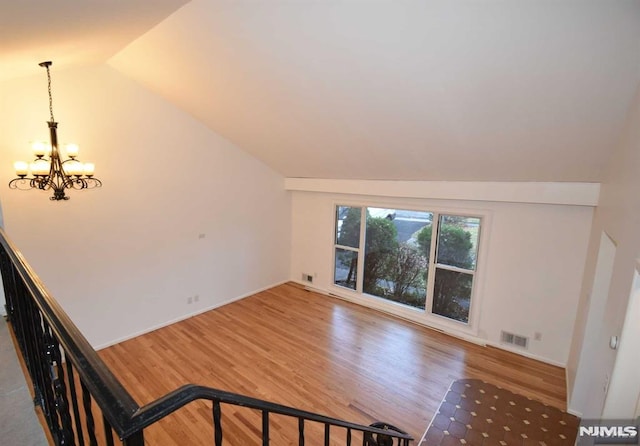 additional living space featuring a notable chandelier, vaulted ceiling, and wood-type flooring