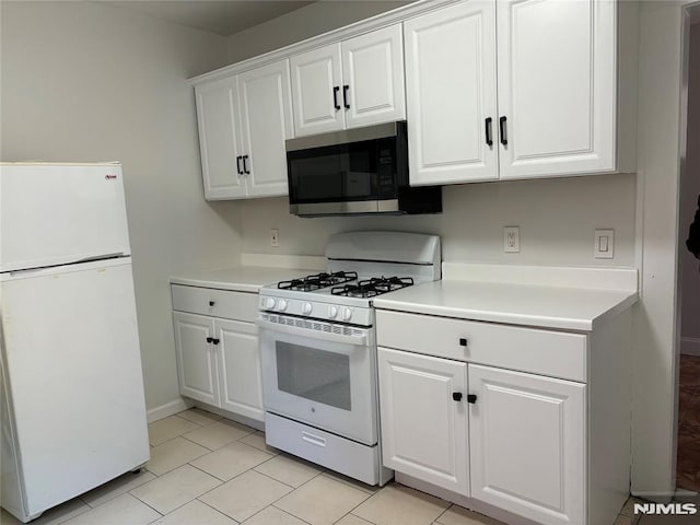 kitchen with white appliances, white cabinetry, and light tile patterned floors