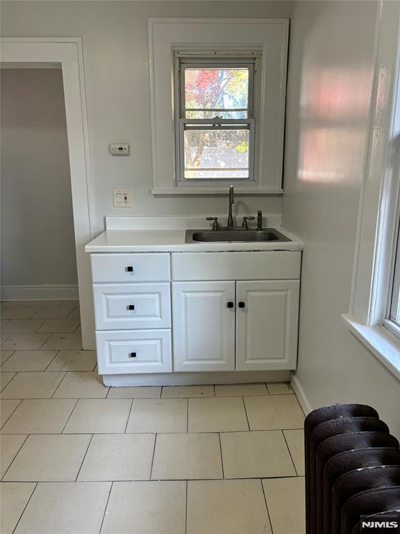 bathroom with tile patterned floors, radiator, and vanity