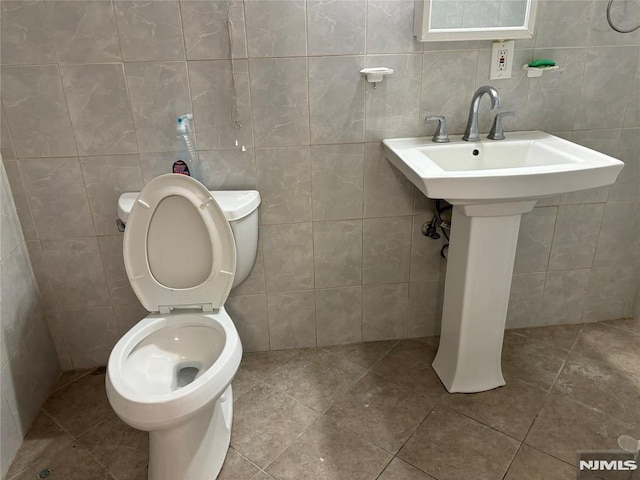 bathroom with tile walls and toilet