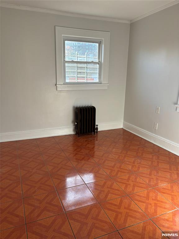 spare room with crown molding and radiator