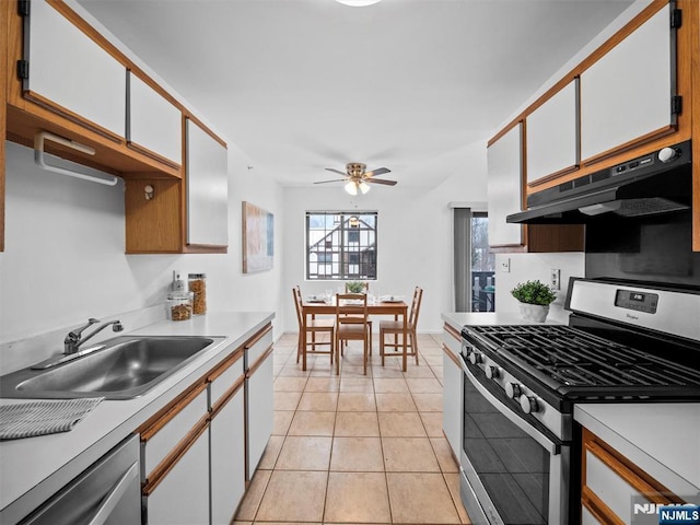 kitchen with appliances with stainless steel finishes, white cabinetry, sink, light tile patterned floors, and ceiling fan