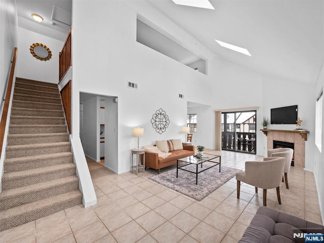 living room with vaulted ceiling with skylight, light tile patterned floors, and a fireplace