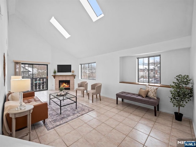 living room with a tiled fireplace, a skylight, high vaulted ceiling, and light tile patterned floors