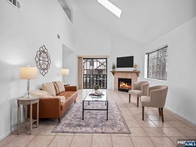 living room with high vaulted ceiling, a skylight, a tile fireplace, and light tile patterned flooring