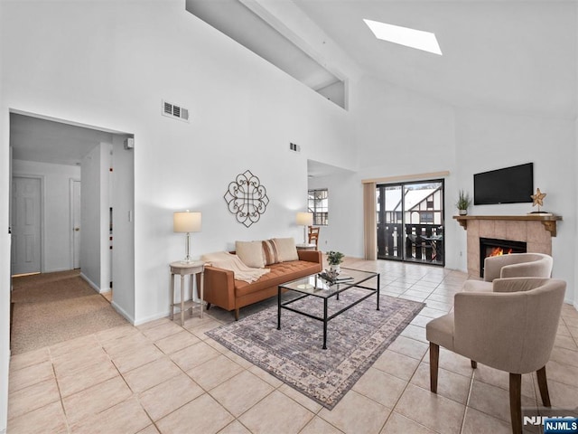 tiled living room with a tiled fireplace and vaulted ceiling with skylight