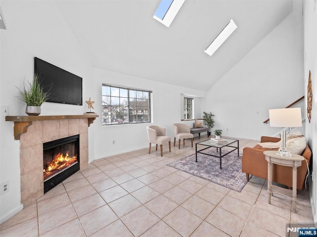 tiled living room featuring a tiled fireplace, a skylight, and high vaulted ceiling