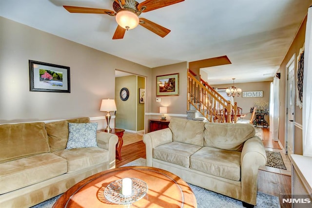 living room featuring light wood-type flooring and ceiling fan with notable chandelier