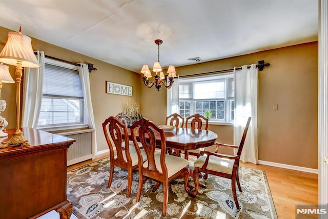 dining room featuring radiator, an inviting chandelier, and light hardwood / wood-style flooring