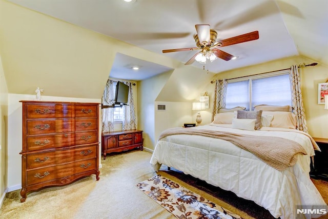 bedroom featuring vaulted ceiling, light colored carpet, ceiling fan, and multiple windows