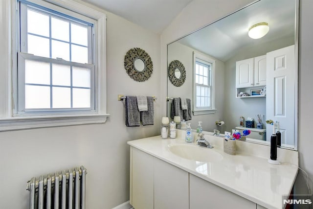 bathroom featuring radiator, vanity, and lofted ceiling