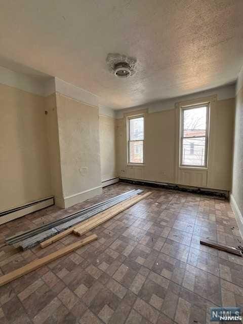 spare room featuring a baseboard radiator and a textured ceiling