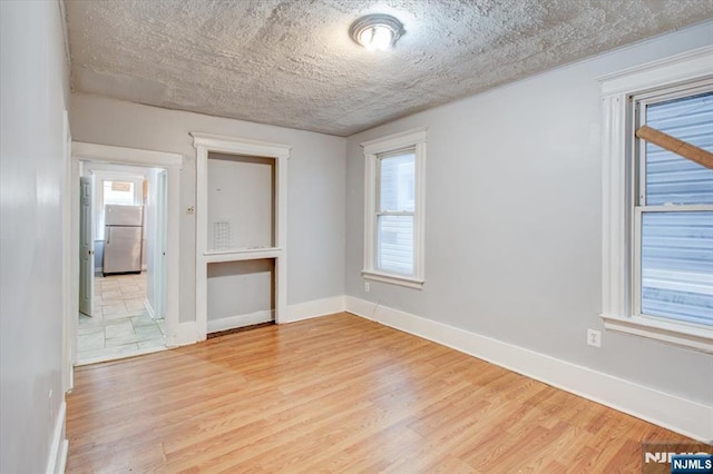 unfurnished room featuring light hardwood / wood-style flooring and a textured ceiling