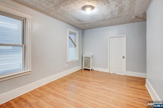 spare room with hardwood / wood-style flooring, a textured ceiling, and a healthy amount of sunlight