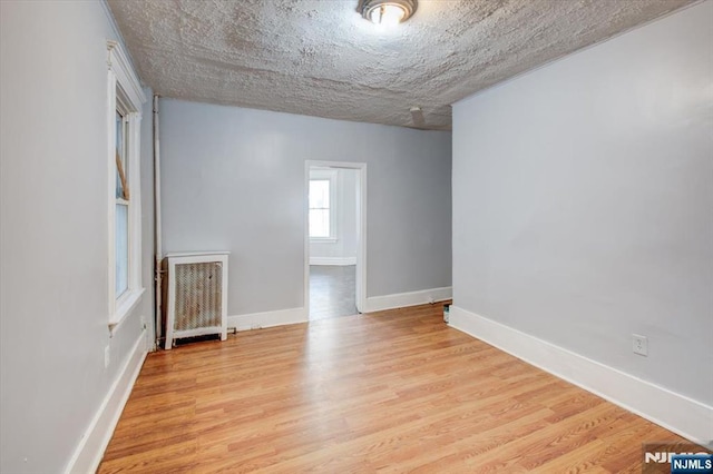 spare room featuring light wood-type flooring and a textured ceiling