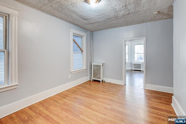 unfurnished room featuring light hardwood / wood-style flooring, plenty of natural light, and a textured ceiling