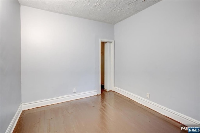 spare room featuring a textured ceiling and wood-type flooring