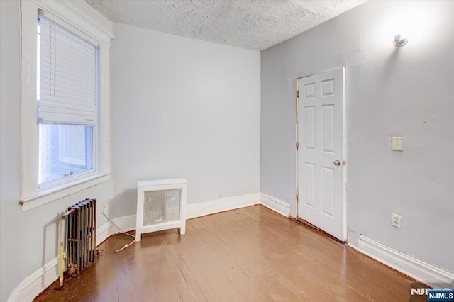 spare room with hardwood / wood-style flooring, radiator, and a textured ceiling