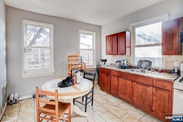 kitchen with sink, light tile patterned floors, tasteful backsplash, and white gas range oven