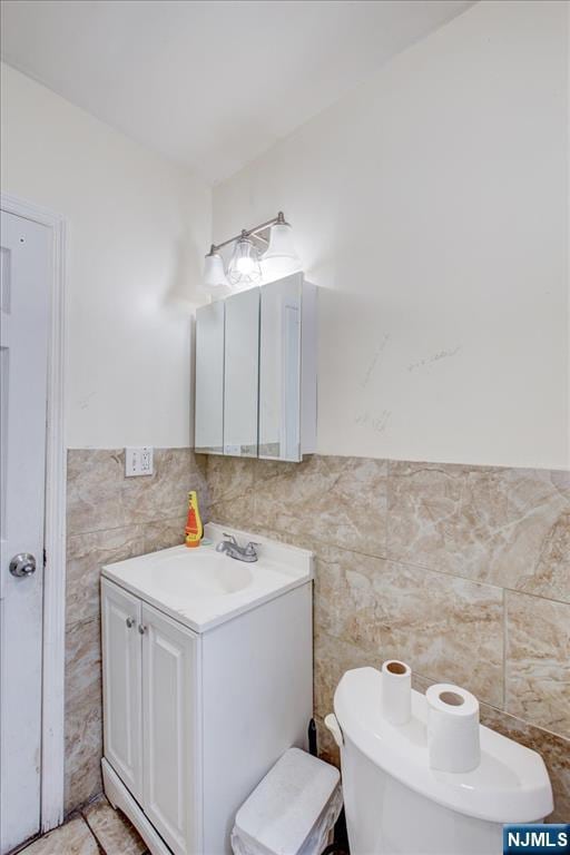 bathroom with vanity, toilet, and tile walls