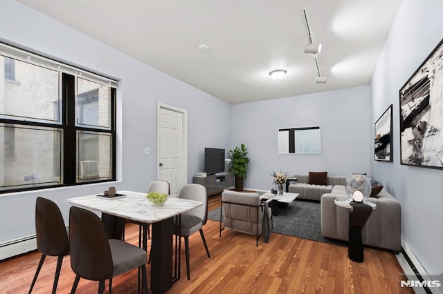 living room featuring light hardwood / wood-style floors, track lighting, and a baseboard radiator