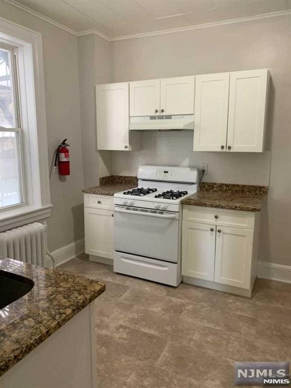 kitchen featuring white gas range, white cabinets, and radiator heating unit