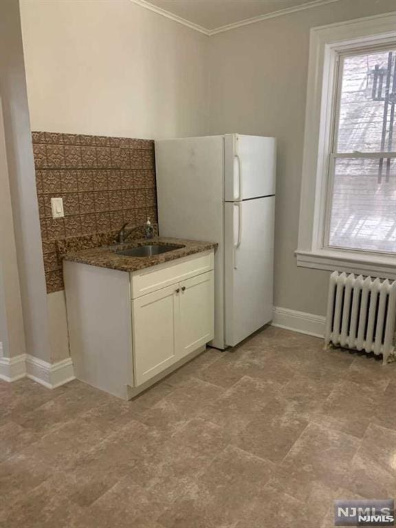 kitchen featuring sink, white cabinetry, white fridge, dark stone countertops, and radiator heating unit