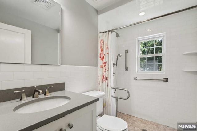 bathroom featuring vanity, decorative backsplash, curtained shower, and toilet