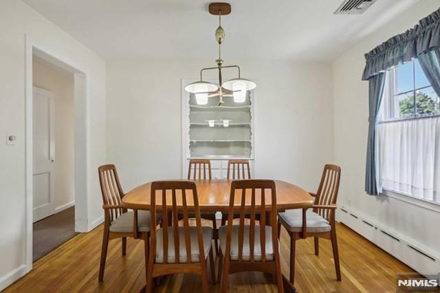 dining area featuring wood-type flooring, baseboard heating, and a notable chandelier