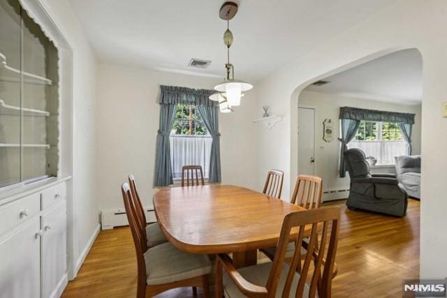 dining area with light hardwood / wood-style flooring, plenty of natural light, and a baseboard heating unit