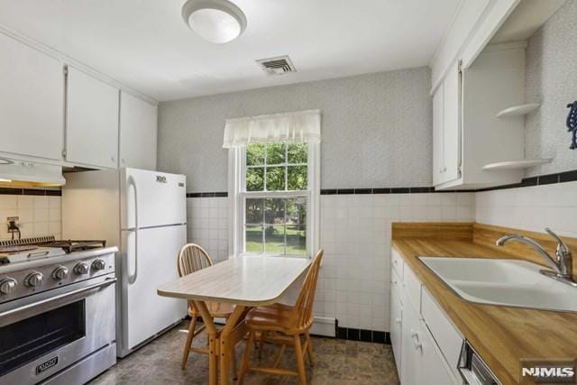 kitchen with white cabinets, white fridge, sink, and high end stainless steel range oven