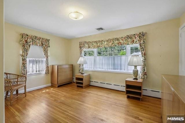 living area featuring a baseboard heating unit and hardwood / wood-style floors